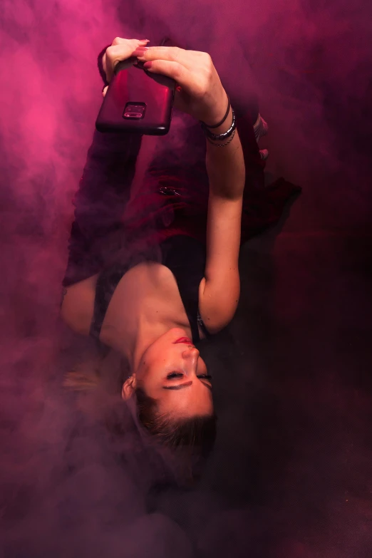 a woman laying on her stomach in a cloud of smoke, a picture, inspired by Nan Goldin, trending on pexels, purple and pink leather garments, nightclub dancing inspired, 8k selfie photograph, high angle