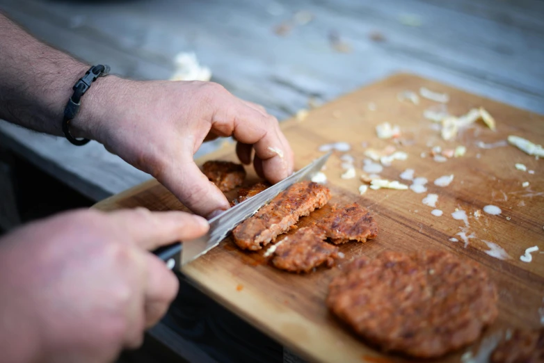 a person cutting up some food on a cutting board, by Niko Henrichon, barbecue, ground meat, crispy quality, arney freytag