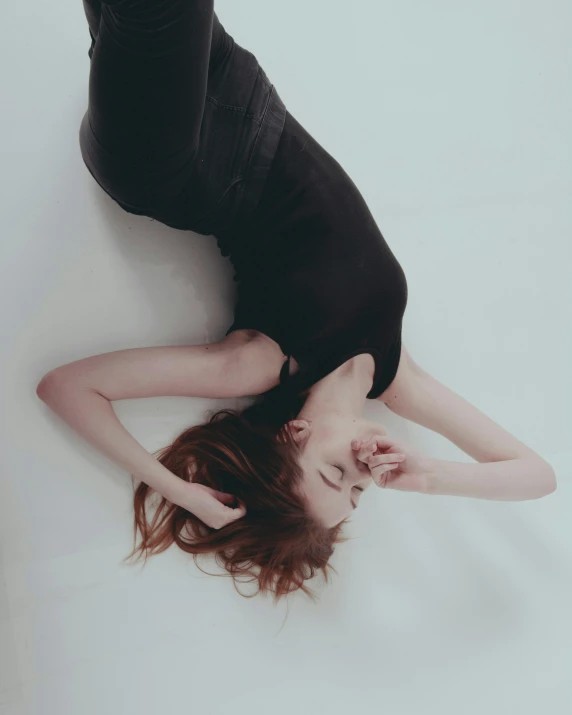 a woman in a black dress laying on the floor, inspired by Elsa Bleda, pexels contest winner, on a pale background, aaaaaaaaaaaaaaaaaaaaaa, bending down slightly, high angle