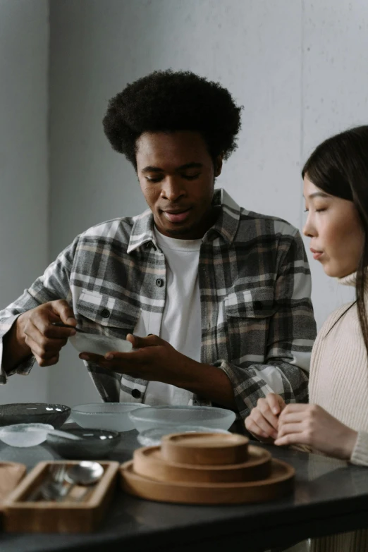 a couple of people that are sitting at a table, trending on pexels, bowl, varying ethnicities, grey, asian male