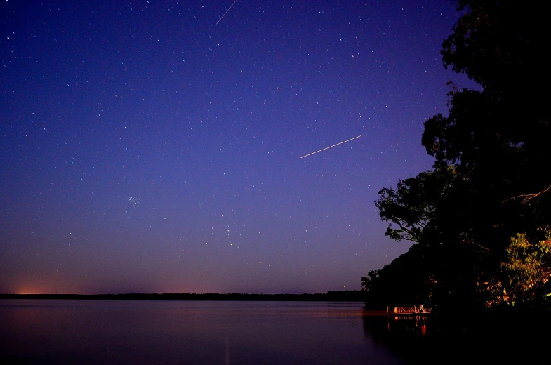 a plane flying over a lake at night, meteor shower, southern cross, evening at dusk, stunning lines