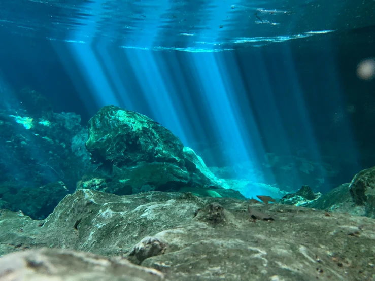 an underwater view of some rocks and water, pexels contest winner, light rays illuminate dust, perfect crisp sunlight, blue and green light, submerged pre - incan temple