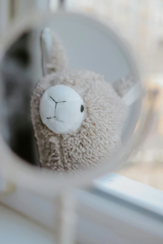 a close up of a stuffed animal in a mirror, unsplash, alpaca, childrens toy, digital image, low - angle shot