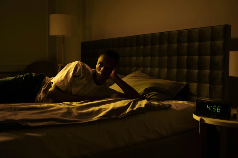 a man laying on a bed in a dimly lit room, maria borges, single light, high resolution, ignant