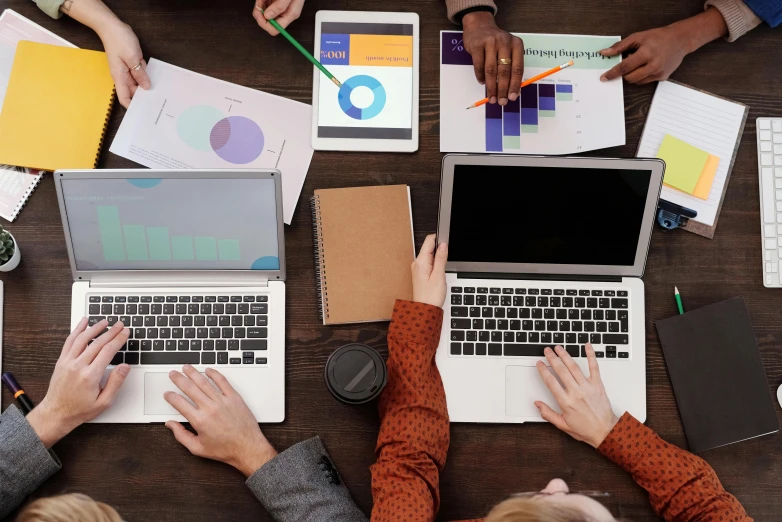 a group of people sitting at a table with laptops, trending on pexels, analytical art, 9 9 designs, round-cropped, charts, closeup - view