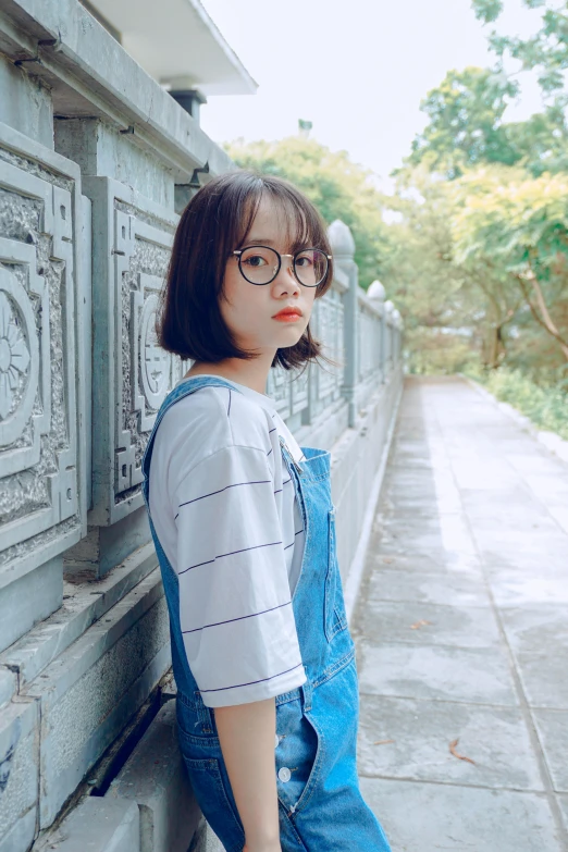 a woman with glasses leaning against a wall, a picture, inspired by Leng Mei, unsplash contest winner, realism, ulzzang, square face, overalls, 奈良美智