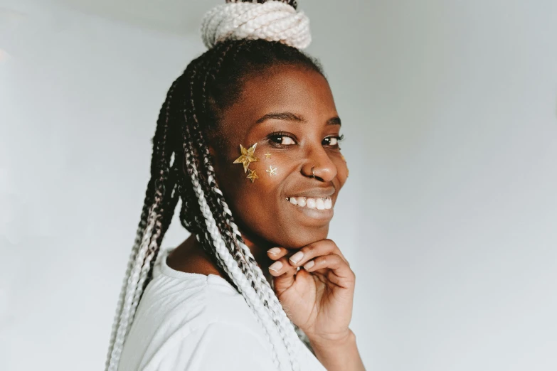 a woman with a star painted on her face, by Dulah Marie Evans, trending on pexels, hurufiyya, cornrows braids, smiling confidently, gold adornements, silver hair ponytail