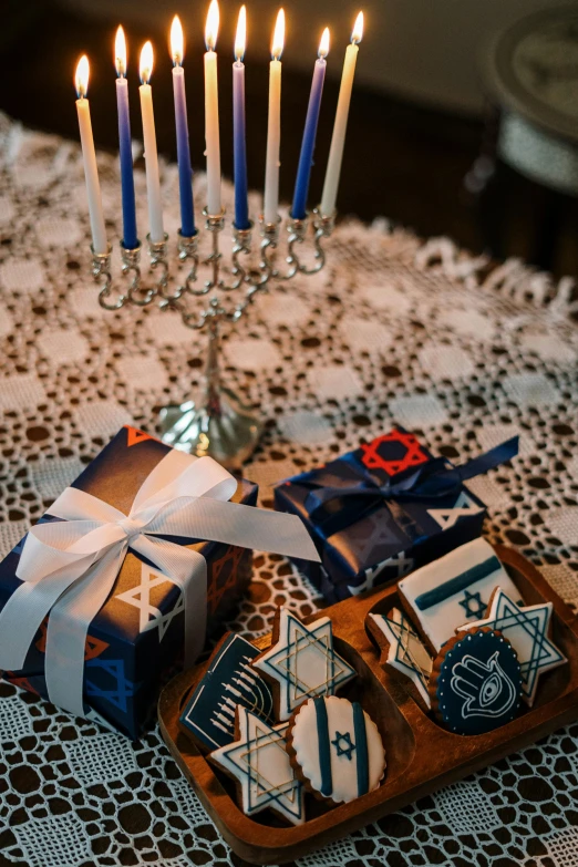 a bunch of cookies sitting on top of a table, candles, hebrew, royal blue colors, presents