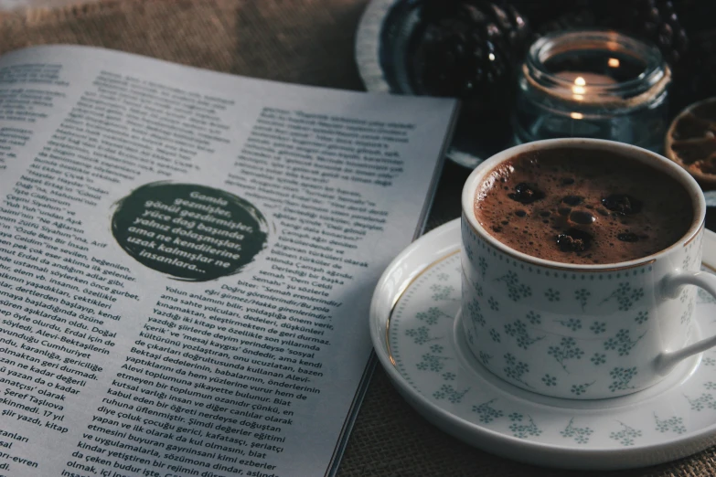 a cup of coffee sitting on top of a saucer, a photo, pexels contest winner, private press, magazine pages, dark-skinned, aykut aydogdu, hot cocoa drink