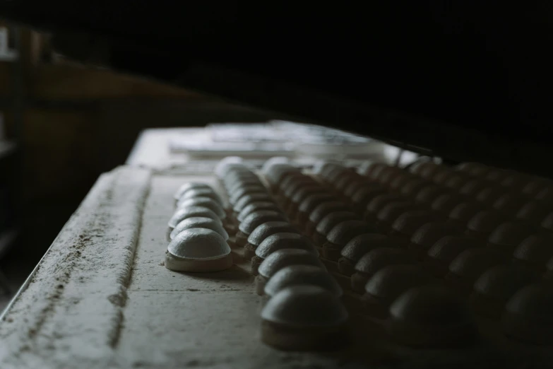 a computer keyboard sitting on top of a wooden desk, a marble sculpture, by Elsa Bleda, unsplash, plasticien, lots of mozzarella balls, stood in a factory, in an ancient vault, moody dim lighting