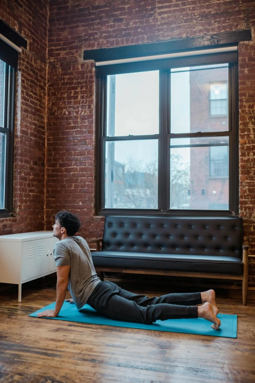 a man sitting on a yoga mat in front of a window, by Carey Morris, unsplash contest winner, nyc, back arched, panoramic shot, dwell