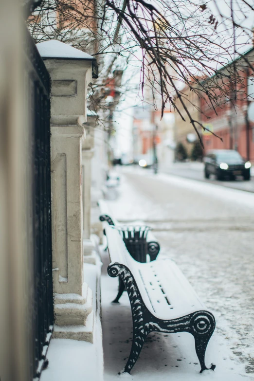 a bench sitting on the side of a road covered in snow, pexels contest winner, colonial era street, during spring, gaze down, city streetscape