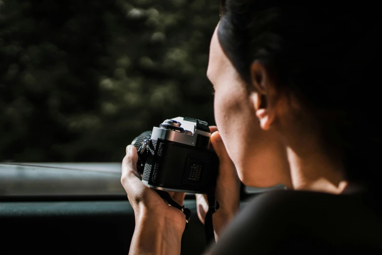 a woman taking a picture with a camera, by Daniel Seghers, pexels contest winner, side profile shot, driving, hasselblad medium format, close - up photograph