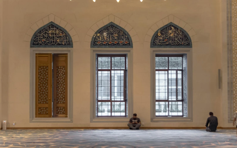 a man sitting on the floor in a large room, a marble sculpture, inspired by Abdullah Gërguri, prayer, through the windows, istock, 2 0 0 0's photo