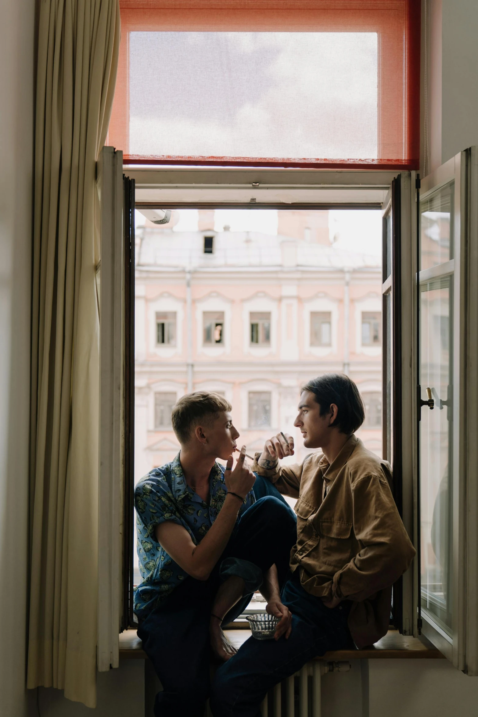 a couple of men sitting on top of a window sill, a portrait, trending on unsplash, young handsome pale roma, lesbian, in doors, in a coffee shop