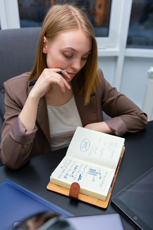 a woman sitting at a desk in front of a laptop, trending on reddit, private press, with book of science, fountain pen, russian academic, thumbnail