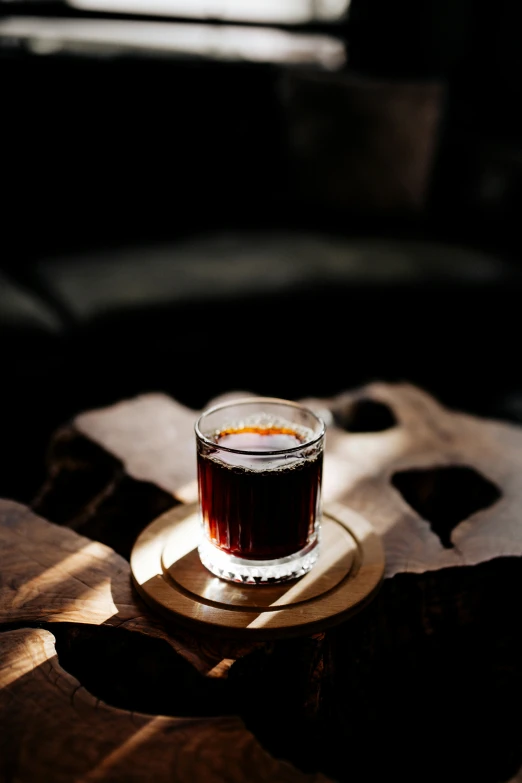 a cup of coffee sitting on top of a wooden table, inspired by Elsa Bleda, sumatraism, glass with rum, dark matter, dark red, absolutely outstanding