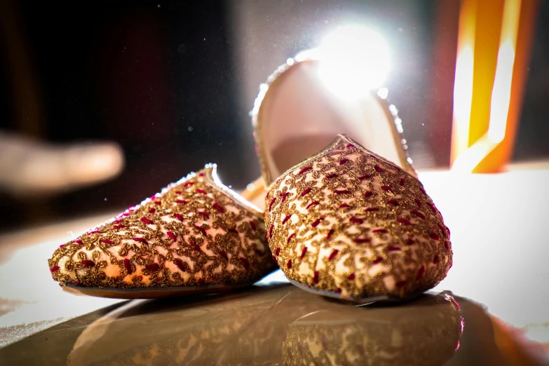 a pair of shoes sitting on top of a table, by Julia Pishtar, pexels contest winner, hurufiyya, arabian night, embellished sequined, maroon, indian style