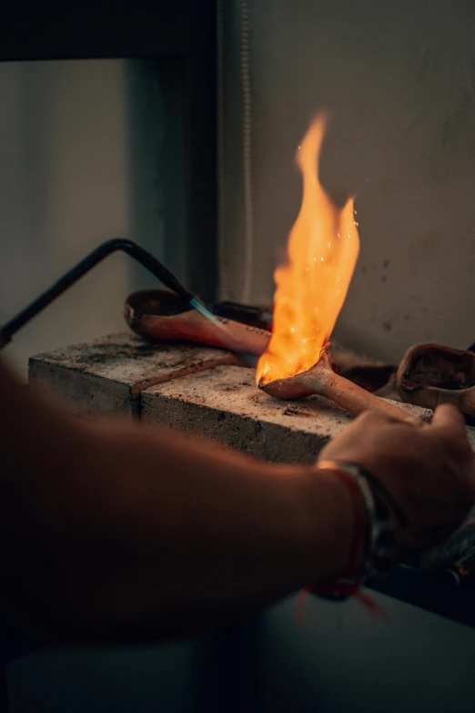 a person holding a piece of metal with a flame coming out of it, a bronze sculpture, inspired by Elsa Bleda, pexels contest winner, process art, made of glowing wax and ceramic, malaysian, gunsmithing, white metal