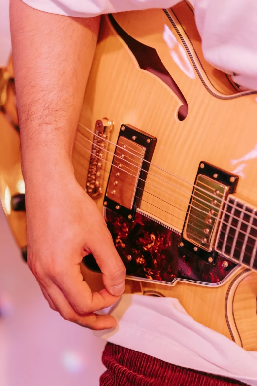 a close up of a person playing a guitar, holding guitars, upclose