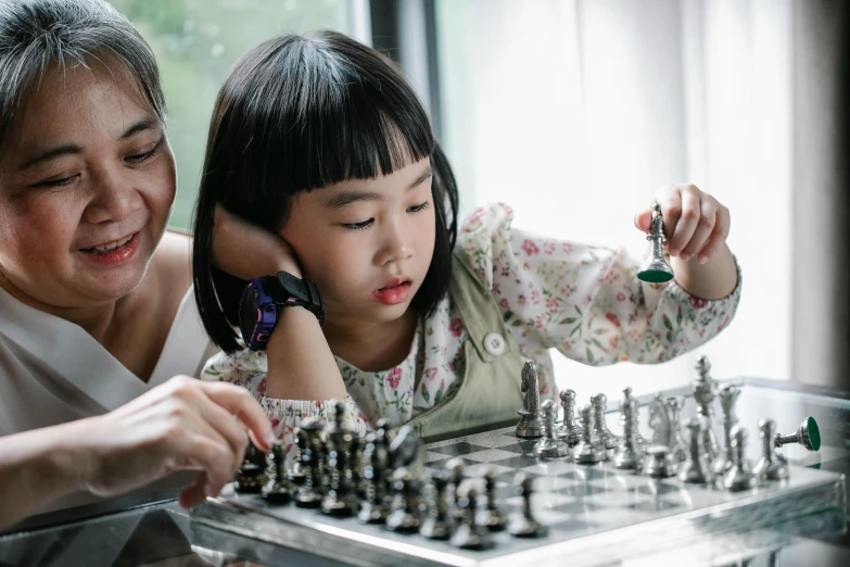 a woman and a child playing a game of chess, pexels contest winner, young asian girl, profile image, thumbnail, father figure image