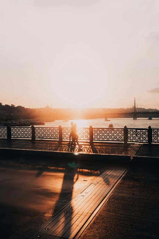 a group of people walking across a bridge at sunset, pexels contest winner, happening, moscow, trending on vsco, seaside, low quality photo