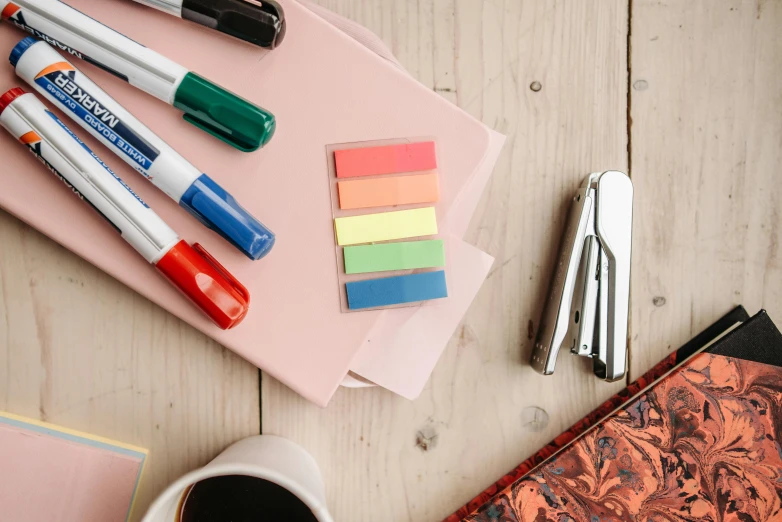 a cup of coffee sitting on top of a wooden table, rainbow coloured rockets, ink on post it note, educational supplies, thumbnail