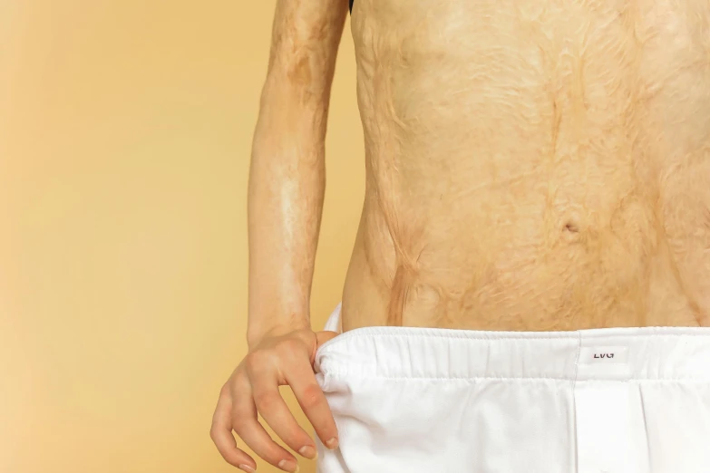 a close up of a person with no shirt on, an album cover, by Ellen Gallagher, trending on pexels, massurrealism, emaciated, stomach skin, yellowed with age, full body with costume