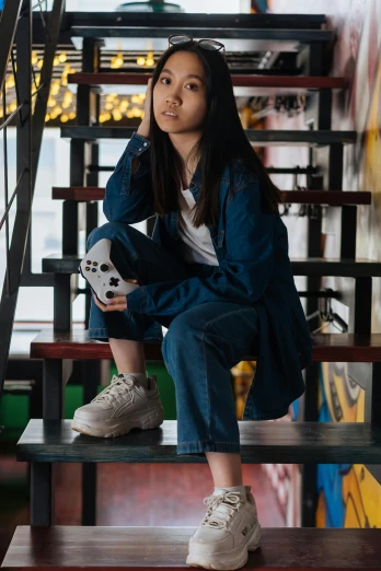 a woman sitting on a set of stairs holding a soccer ball, a picture, by Sebastian Vrancx, pexels contest winner, young asian girl, double denim, sitting in a cafe, sneaker photo