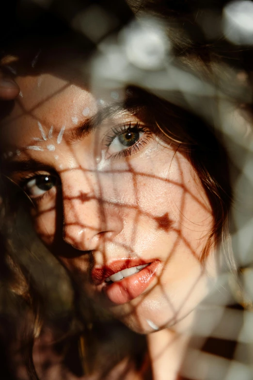 a close up of a woman's face behind a fence, a picture, inspired by Elsa Bleda, trending on pexels, portrait of ana de armas, fishnet, play of light, high angle closeup portrait