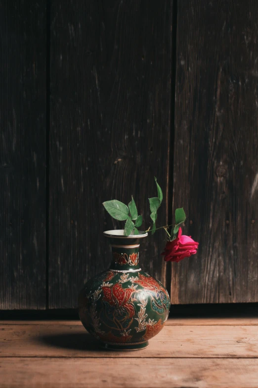 a red rose in a vase on a wooden table, inspired by Miyagawa Isshō, unsplash, cloisonnism, copper and emerald, old color photograph, imari, curated collections