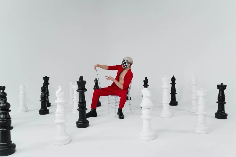 a man sitting in a chair surrounded by chess pieces, an album cover, by Emma Andijewska, pexels contest winner, red suit, mrbeast, full body picture, youtube thumbnail