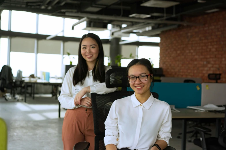 two women standing next to each other in an office, a picture, inspired by Ruth Jên, unsplash, gutai group, avatar image, sitting on chair, engineer, closeup portrait shot