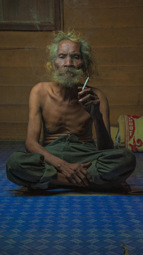 a man sitting on the floor smoking a cigarette, an album cover, inspired by Steve McCurry, pexels contest winner, sumatraism, grizzled, two skinny old people, ((portrait)), south east asian with long