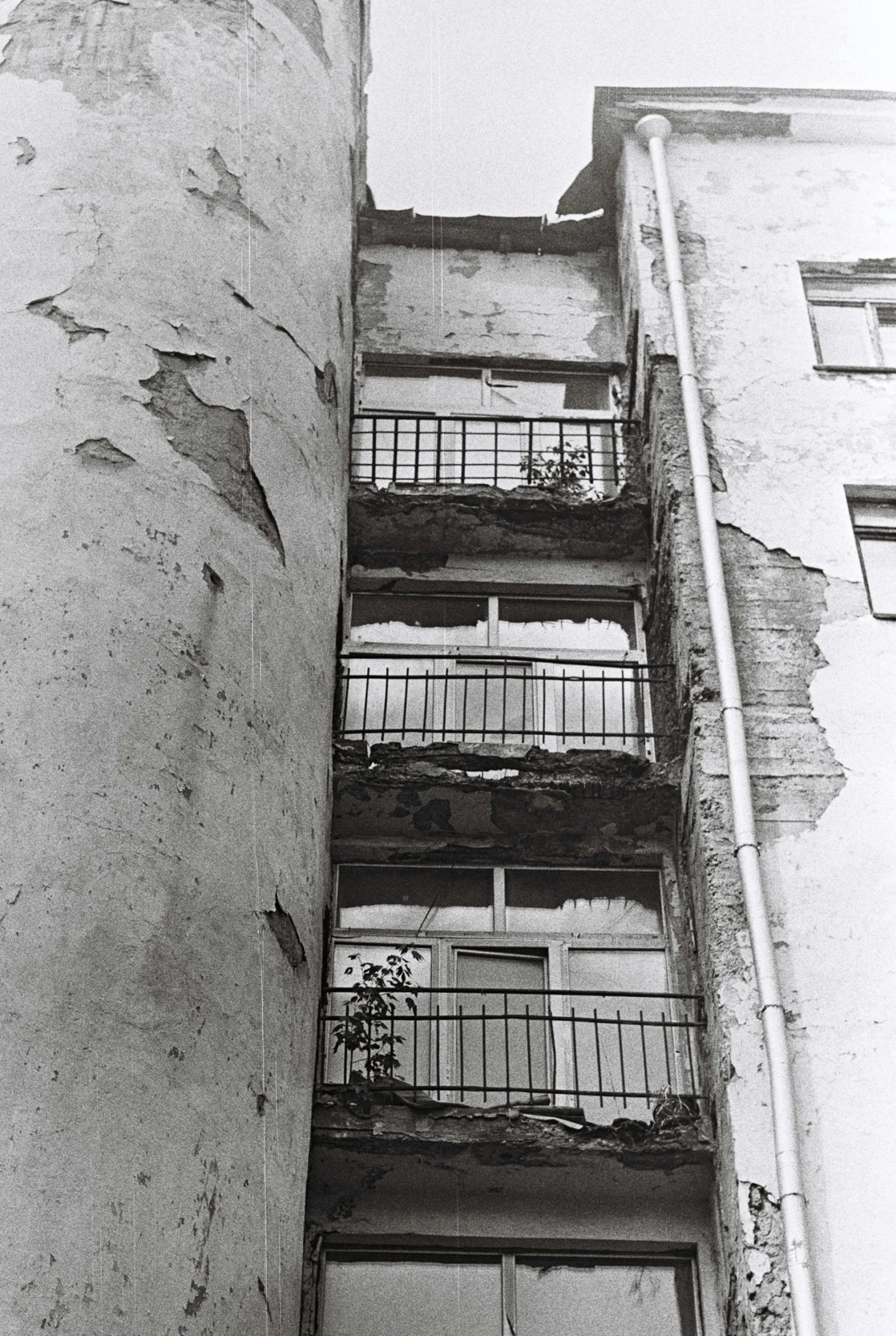 a black and white photo of a tall building, an album cover, inspired by André Kertész, flickr, brutalism, shattered crumbling plaster, soviet apartment buildings, balcony scene, berlin 1 9 8 2