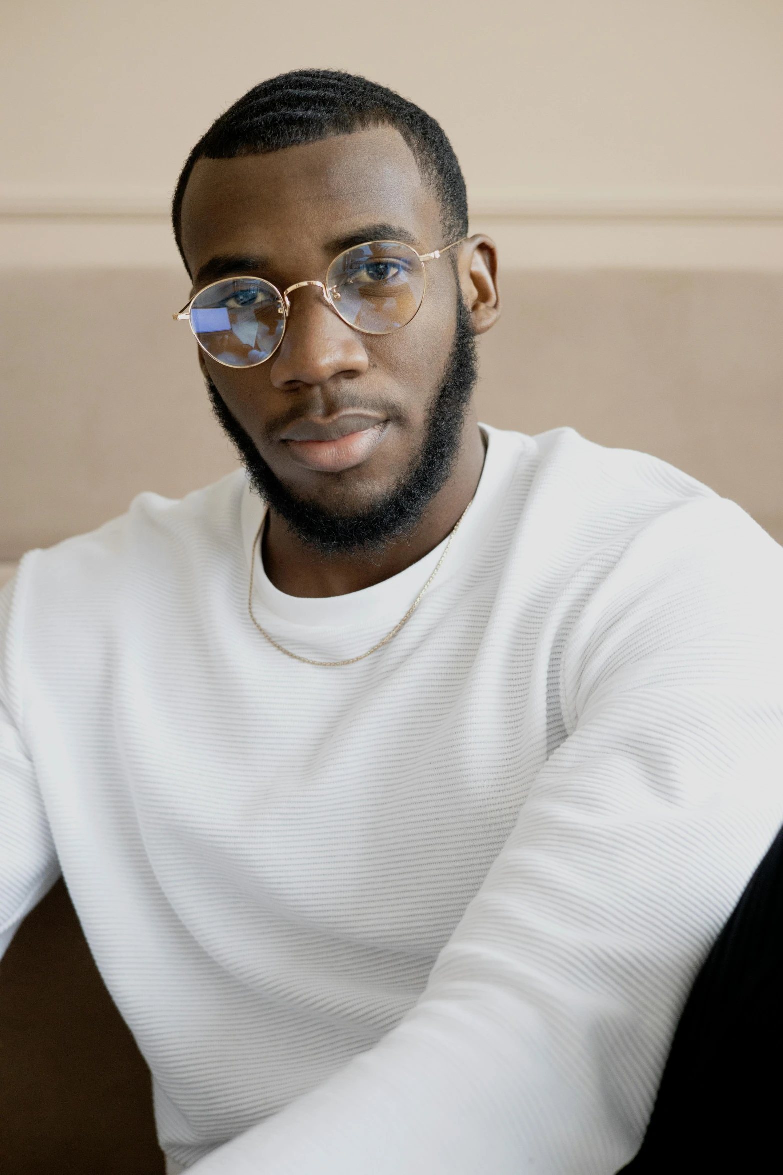 a man wearing glasses sitting on a couch, inspired by Theo Constanté, trending on pexels, delicate androgynous prince, man is with black skin, wearing a white sweater, portrait of tall