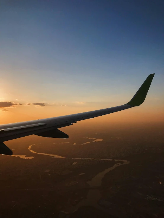 an airplane wing with the sun setting in the background, pexels contest winner, happening, photo of green river, jakarta, profile picture 1024px, plain stretching into distance