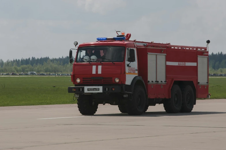 a red fire truck driving down a runway, a picture, by Attila Meszlenyi, hurufiyya, 15081959 21121991 01012000 4k, square, on a landing pad, high quality photo