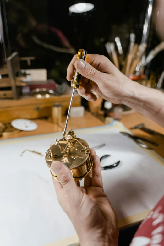 a close up of a person working on a clock, inspired by Frederik de Moucheron, gold and luxury materials, lasso tool, holding an epée, exploded parts assembly