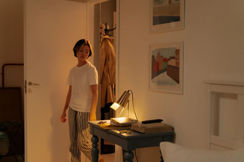 a woman standing in a bedroom next to a desk, inspired by Fei Danxu, happening, contrejour lighting, easy to use, late summer evening, illuminated lighting