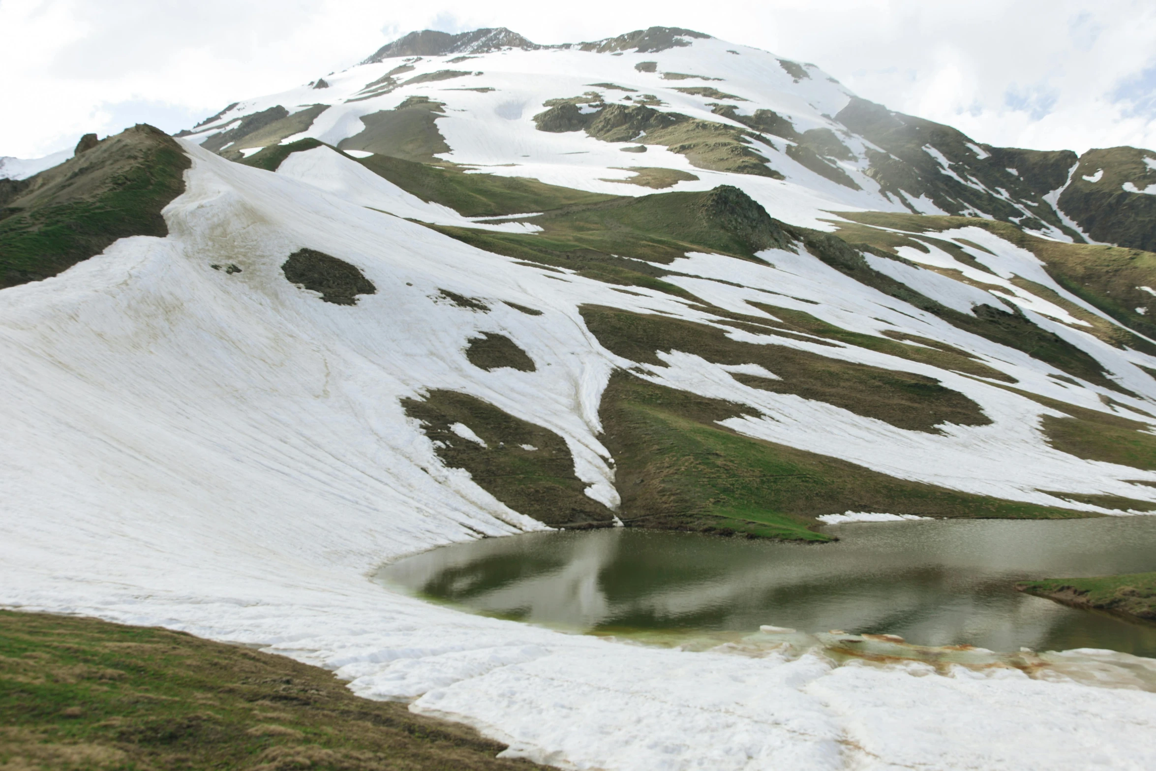 a snow covered mountain with a lake in the middle, by Muggur, hurufiyya, full of greenish liquid, ligjt trail, nature photo