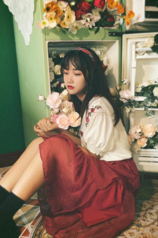 a woman sitting on the floor in front of a refrigerator, a picture, inspired by Kim Jeong-hui, tumblr, dressed in a frilly ((ragged)), red flowers, male ulzzang, profile image