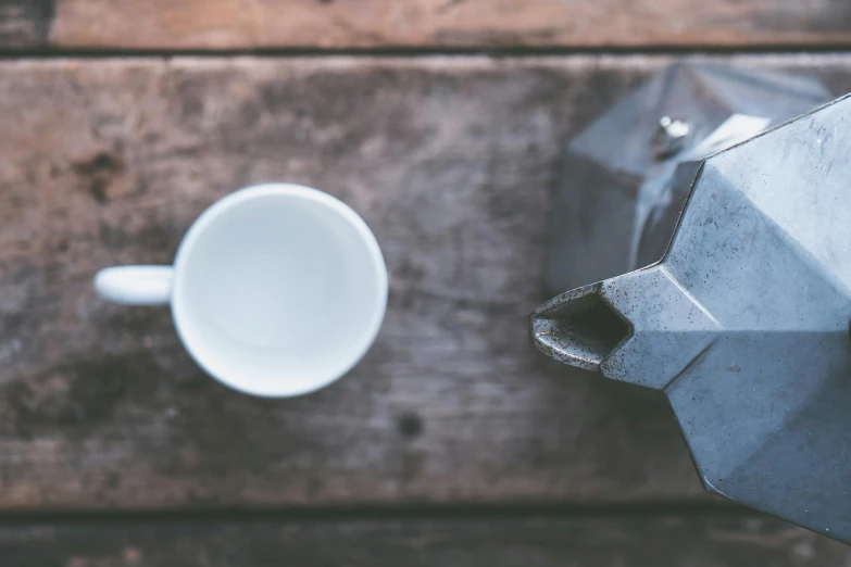 a coffee pot sitting on top of a wooden table, by Romain brook, unsplash, ideal polyhedron, grey metal body, two, white