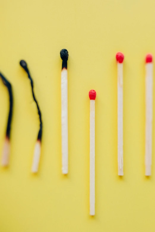 a row of matches on a yellow background, a picture, pexels, minimalism, stressed and burnt out, black chalk, a brightly colored, micro expressions