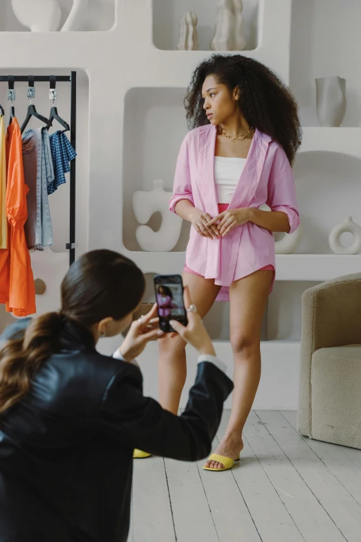 a woman taking a picture of another woman in a room, trending on pexels, renaissance, bra and shorts streetwear, wearing a light - pink suit, commercial, tech robes