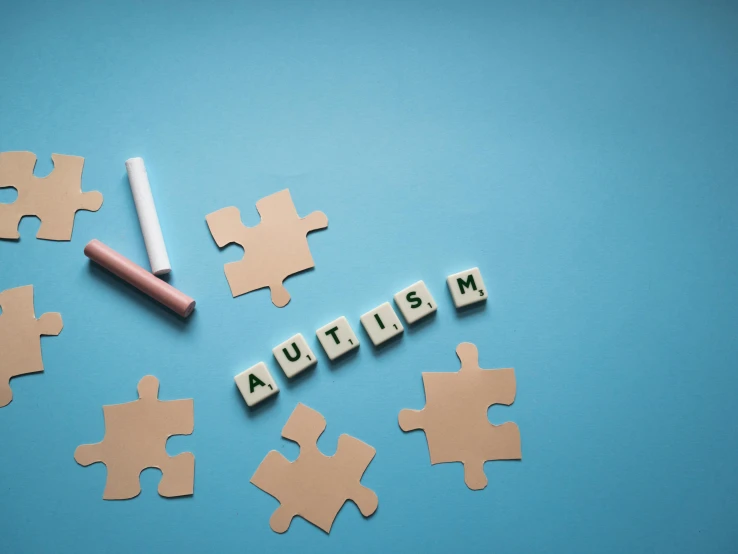 the word autism spelled with puzzle pieces on a blue background, by Adam Marczyński, shutterstock, aestheticism, flatlay, various items, instagram picture, robotics