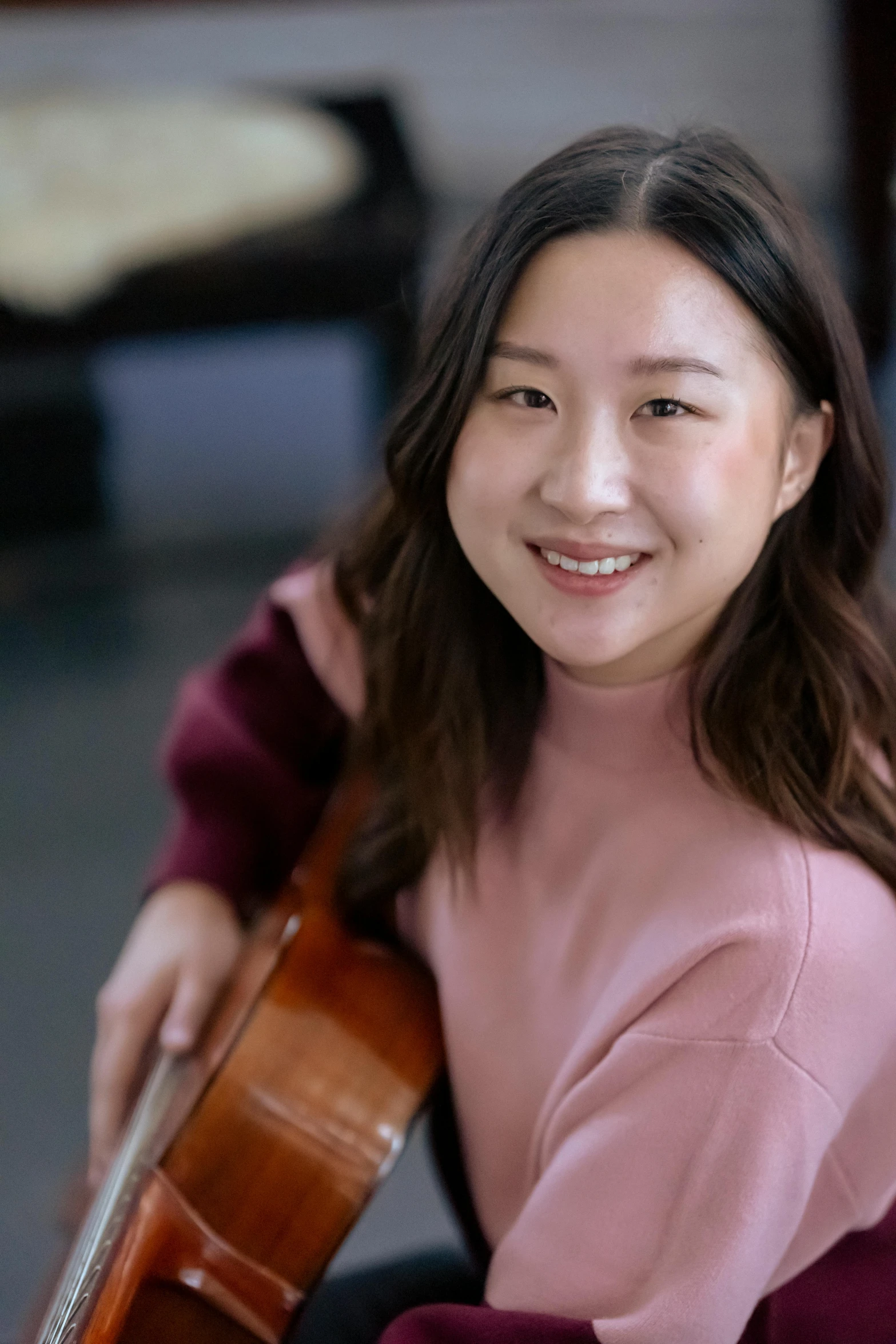 a woman is smiling while holding a violin, by helen huang, portrait image