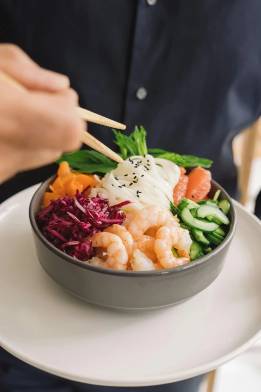 a person eating a bowl of food with chopsticks, daily specials, vibrant foliage, shrimp, prettt