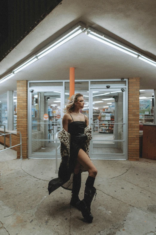 a woman in a black dress standing in front of a store, an album cover, trending on pexels, happening, inside a gas station, cinematic outfit photo, joel fletcher, exiting store