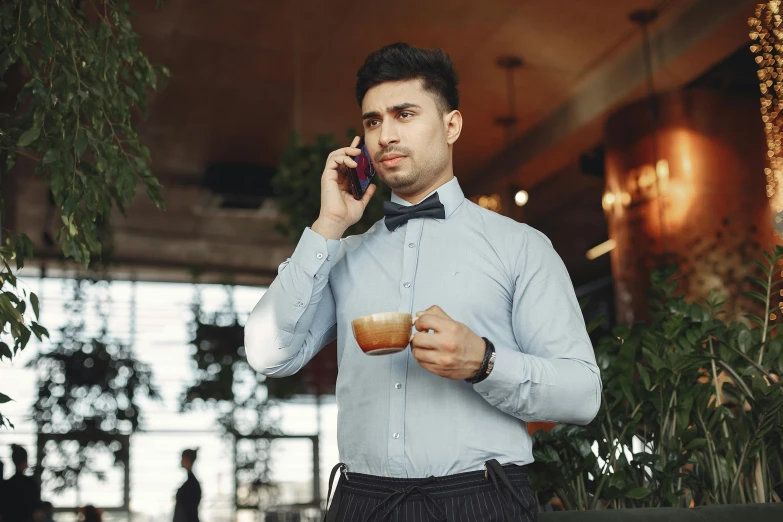 a man in a bow tie talking on a cell phone, by Adam Marczyński, trending on pexels, renaissance, arabica style, aussie baristas, wearing a light blue shirt, thumbnail